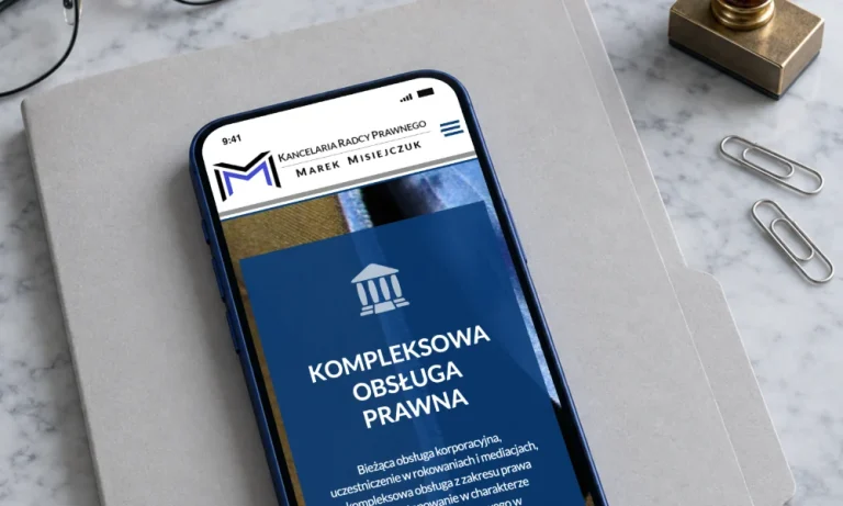 Strona kancelarii radcy prawnego Marka Misiejczuka na telefonie leżącym na szarej teczce akt, obok pieczątka i spinacze